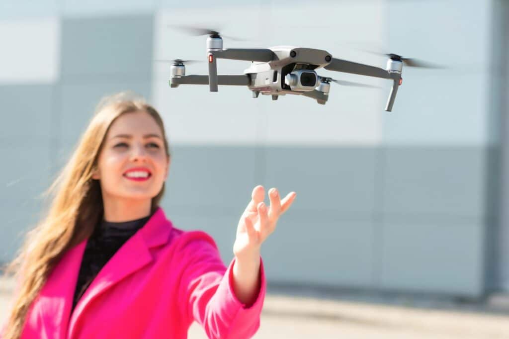 Start the drone, launching from hands. Defocused young woman in the background, focus on the drone