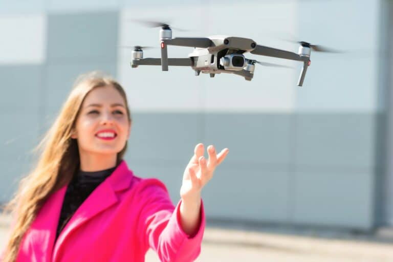 Start the drone, launching from hands. Defocused young woman in the background, focus on the drone