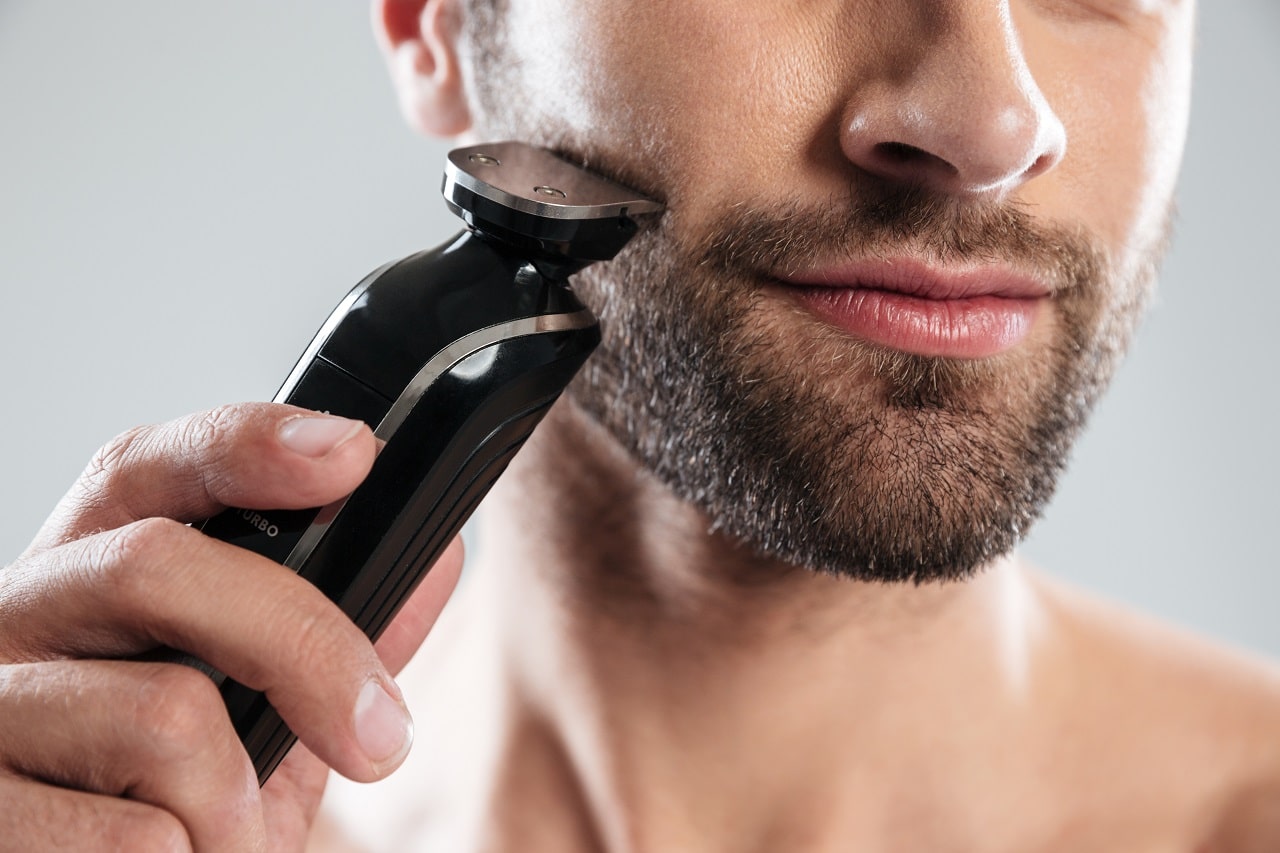 Un homme qui se rase la barbe à l'aide d'une tondeuse.