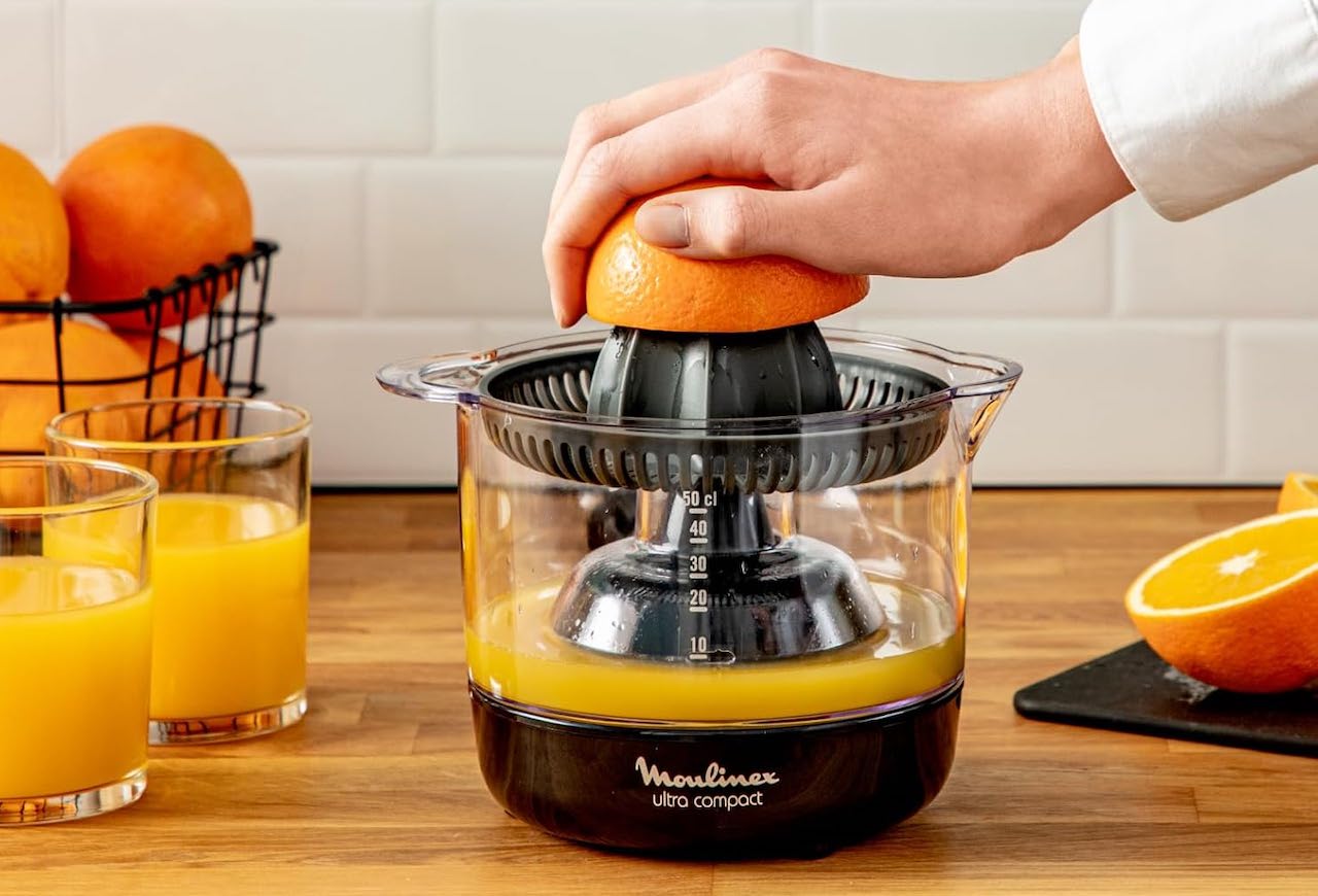 Un presse-agrume de la marque Moulinex. Une personne est en train de presser une orange avec.