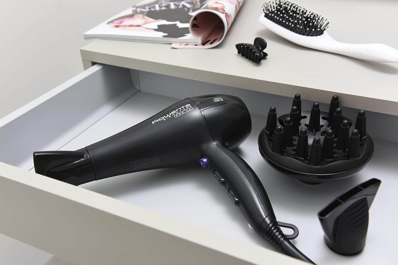 Un sèche-cheveux de la marque Rowenta disposé dans le tiroir d'une coiffeuse.