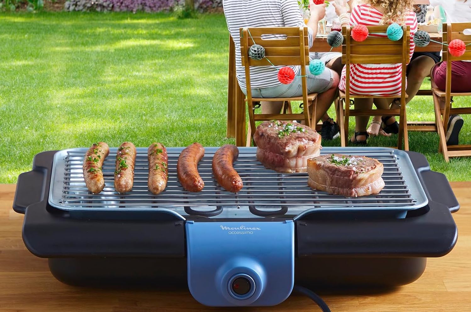 Un petit barbecue électrique de la marque Moulinex disposé sur une table de jardin.