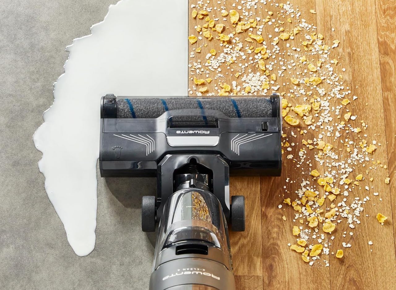 Un aspirateur de la marque Rowenta. Il aspire sur deux sols différents : un parquet où il y a des céréales, et une moquette couverte de lait.