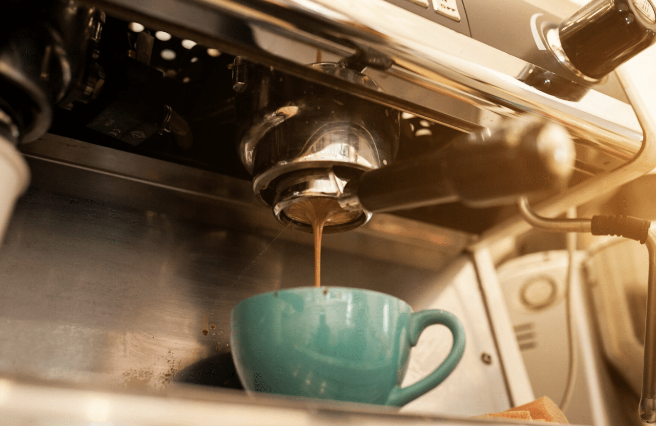 Une machine à café qui sert le café dans une tasse verte.
