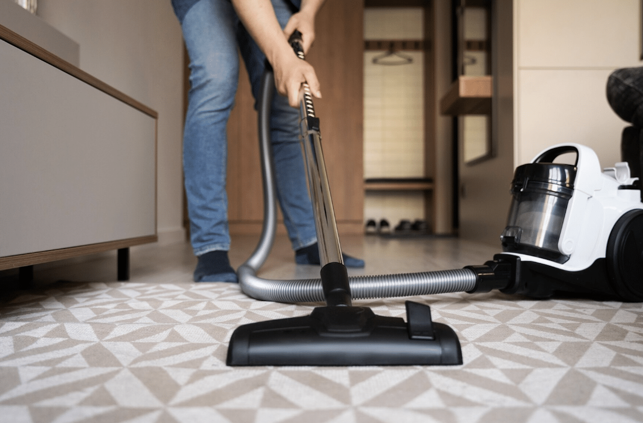 Un homme en train de passer l'aspirateur sur son tapis.