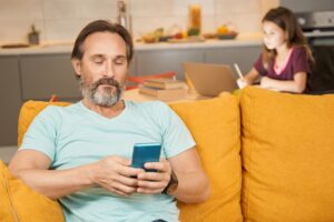 Adult man is using smartphone on sofa in living room