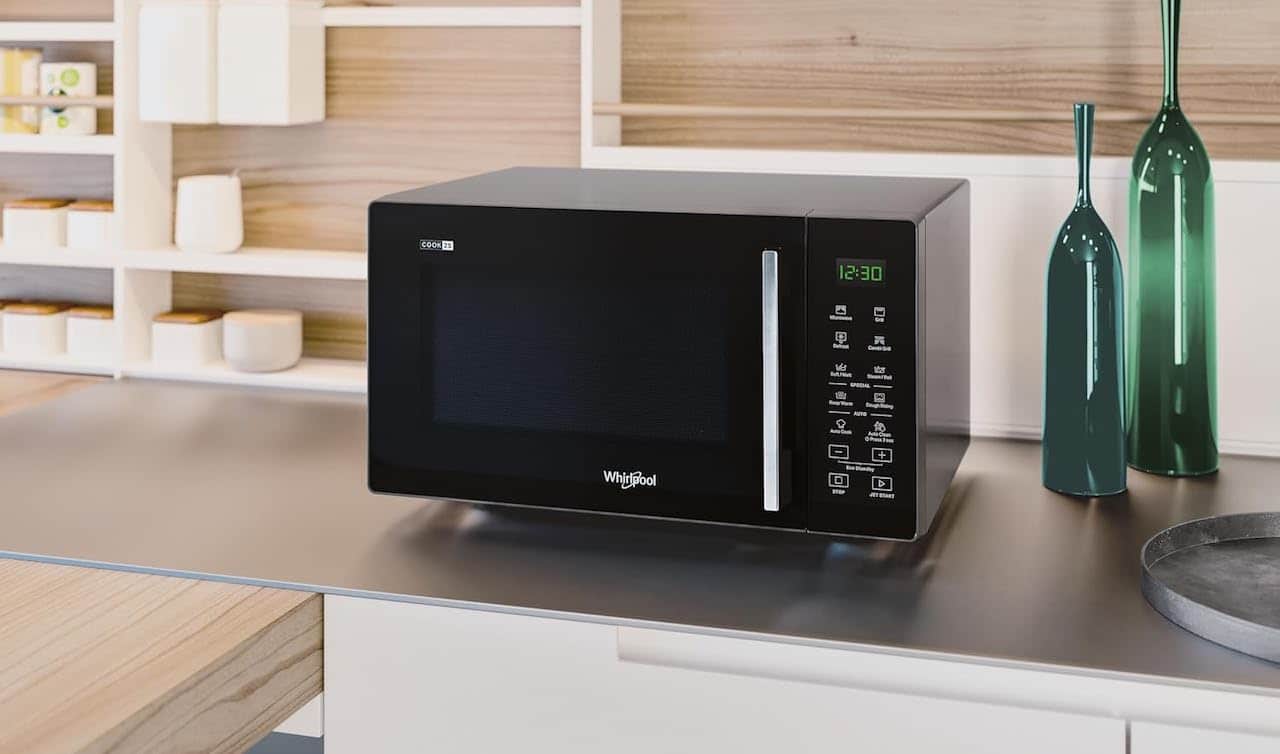 Un four à micro-ondes de la marque Whirlpool posé sur un plan de travail.