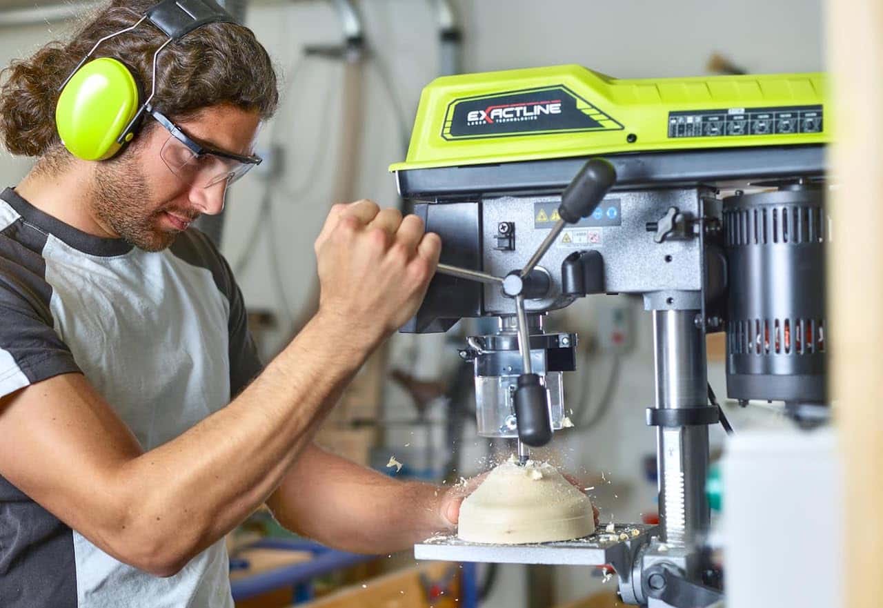 Un homme utilisant une perceuse à colonne filaire de la marque Ryobi.