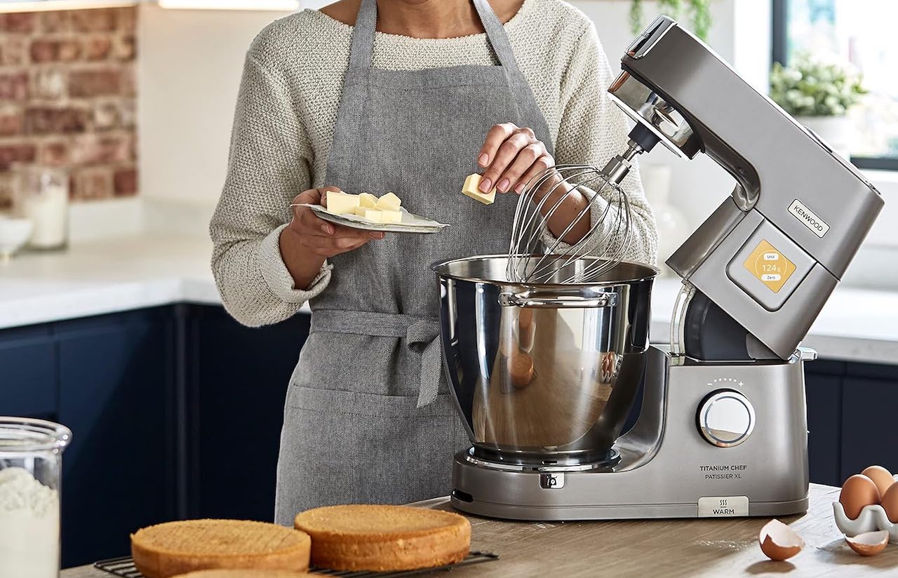 Une femme en train de cuisiner avec un robot pâtissier de la marque Kenwood.