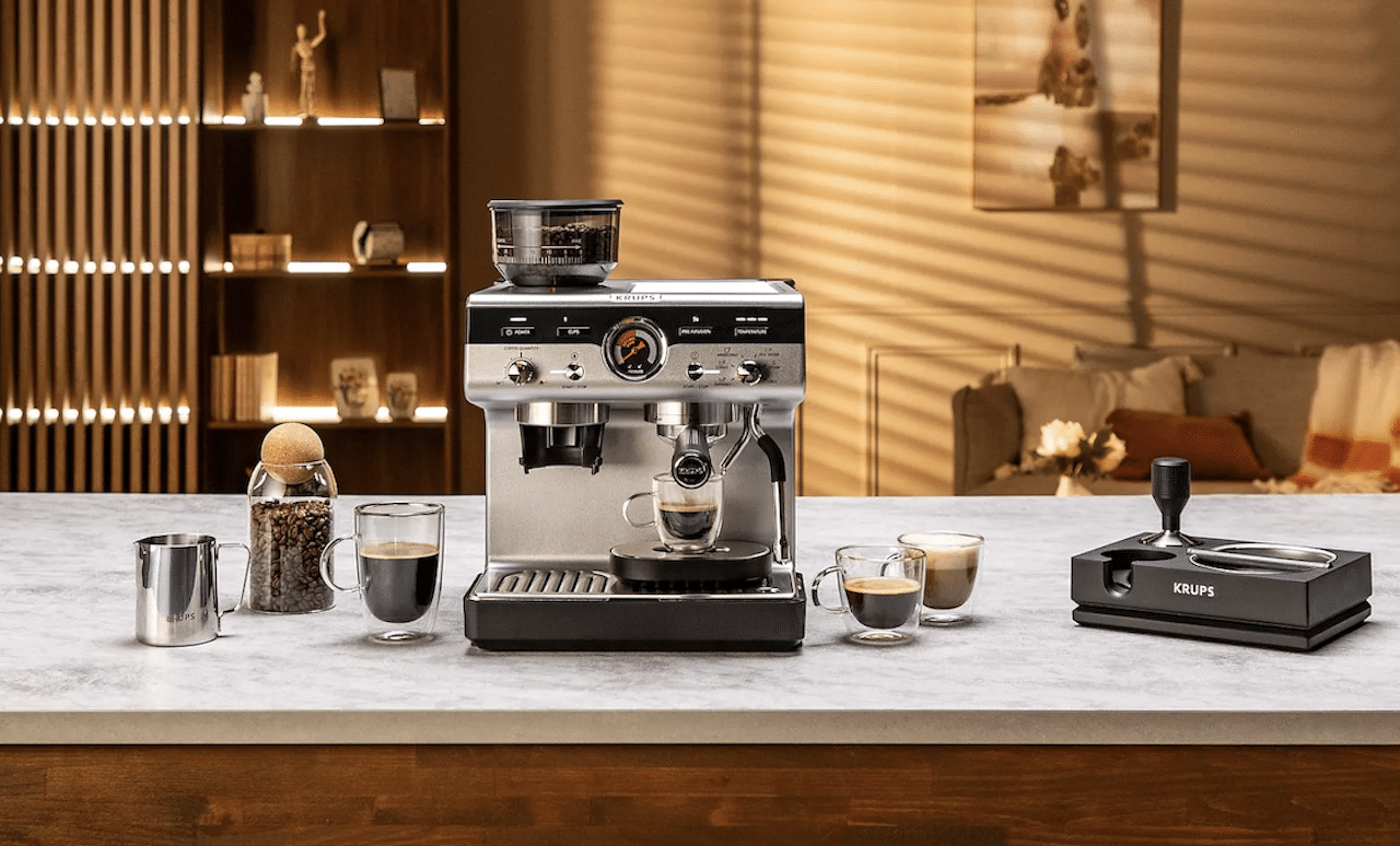 Une machine à expresso de la marque Krups posée sur un plan de travail.