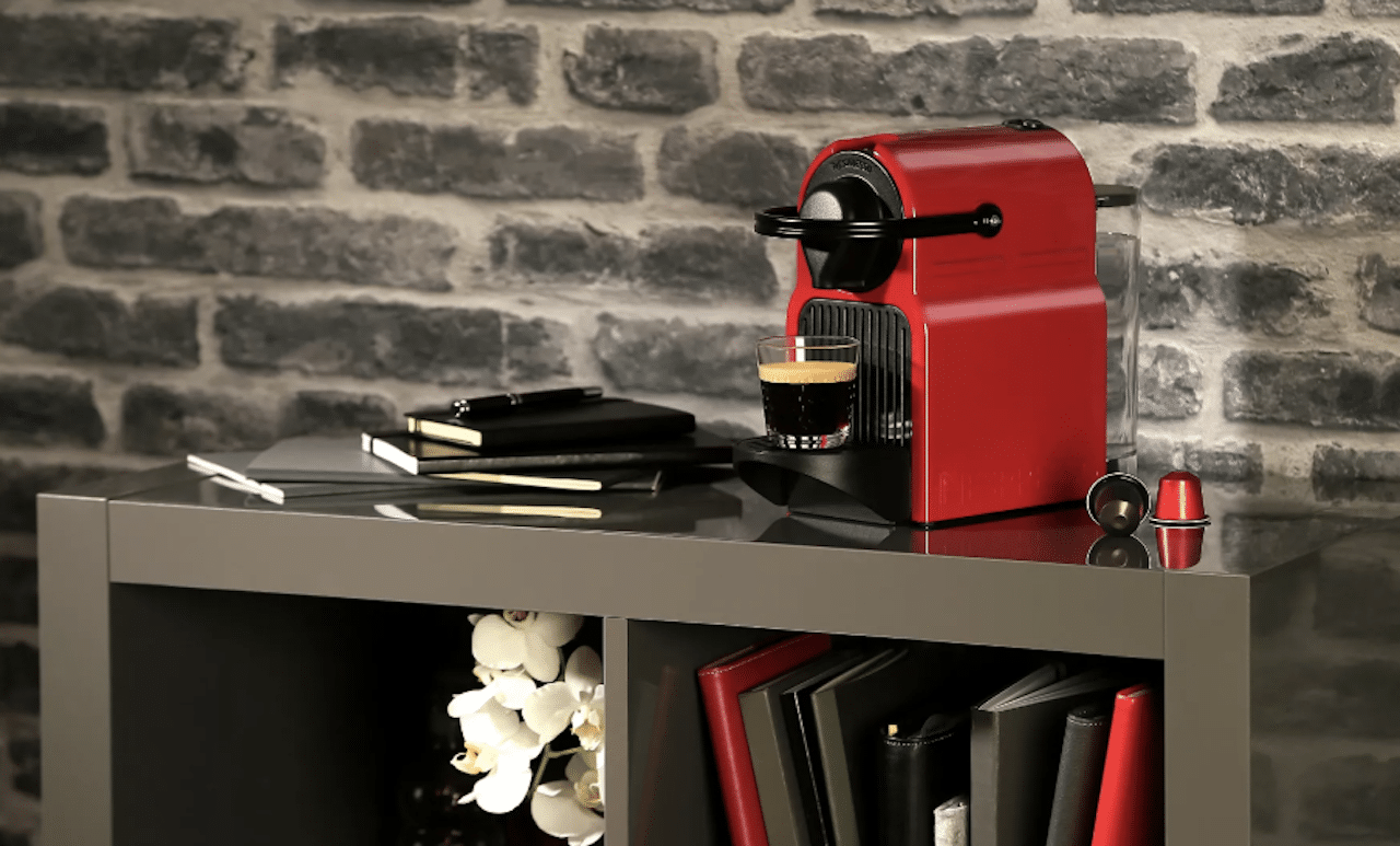 Une cafetière Nespresso de la marque Krups posée sur un meuble de salon.