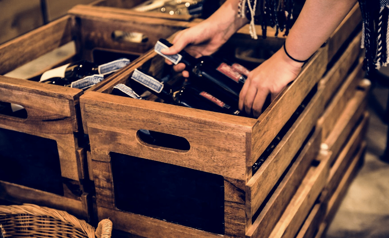 Un personne qui prends des bouteilles de vin pour les conserver dans une cave à vin de la marque Vin-Sur-Vin.