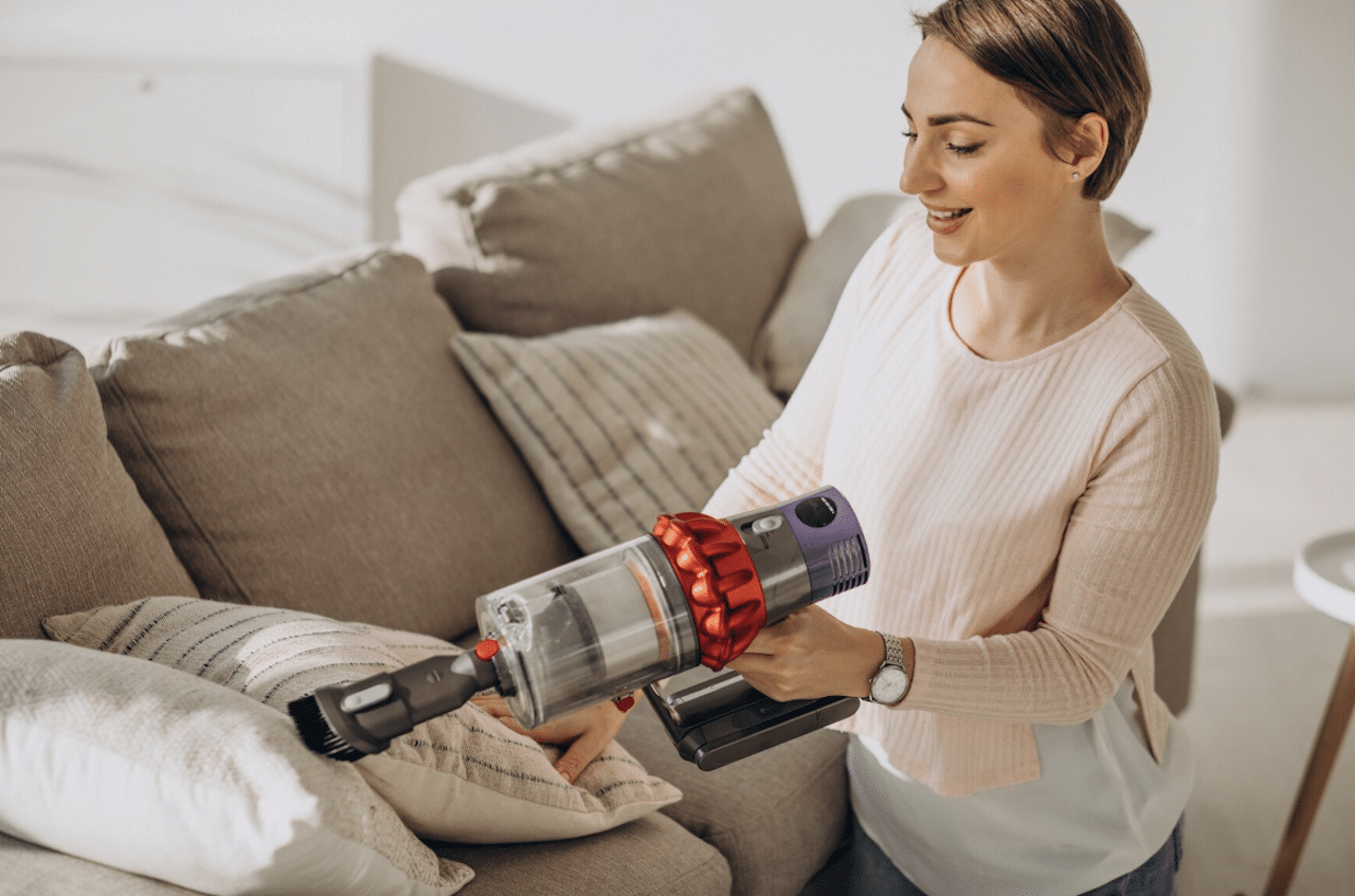 Une femme en train d'aspirer des coussins avec un aspirateur.