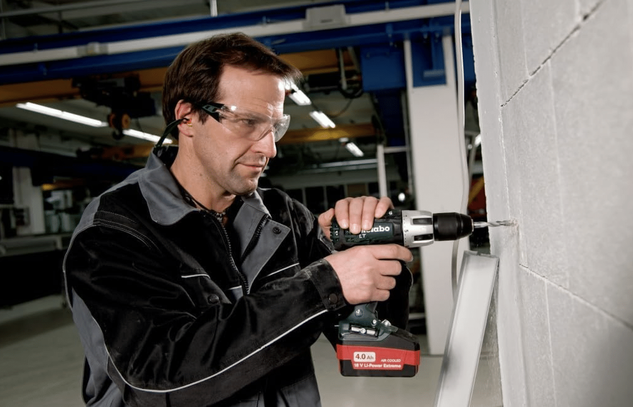 Un homme en train d'utiliser une perceuse à percussion de la marque Metabo.