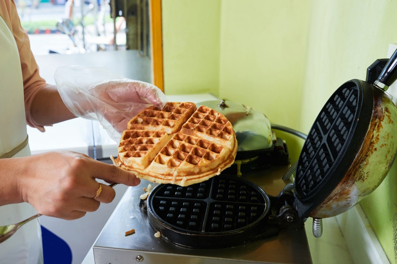 Une femme sortant une énorme gaufre d'un gaufrier