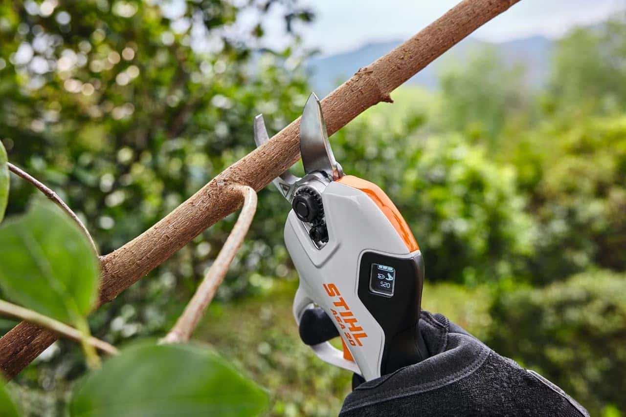 Une personne en train d'utiliser un sécateur sans fil de la marque Stihl.