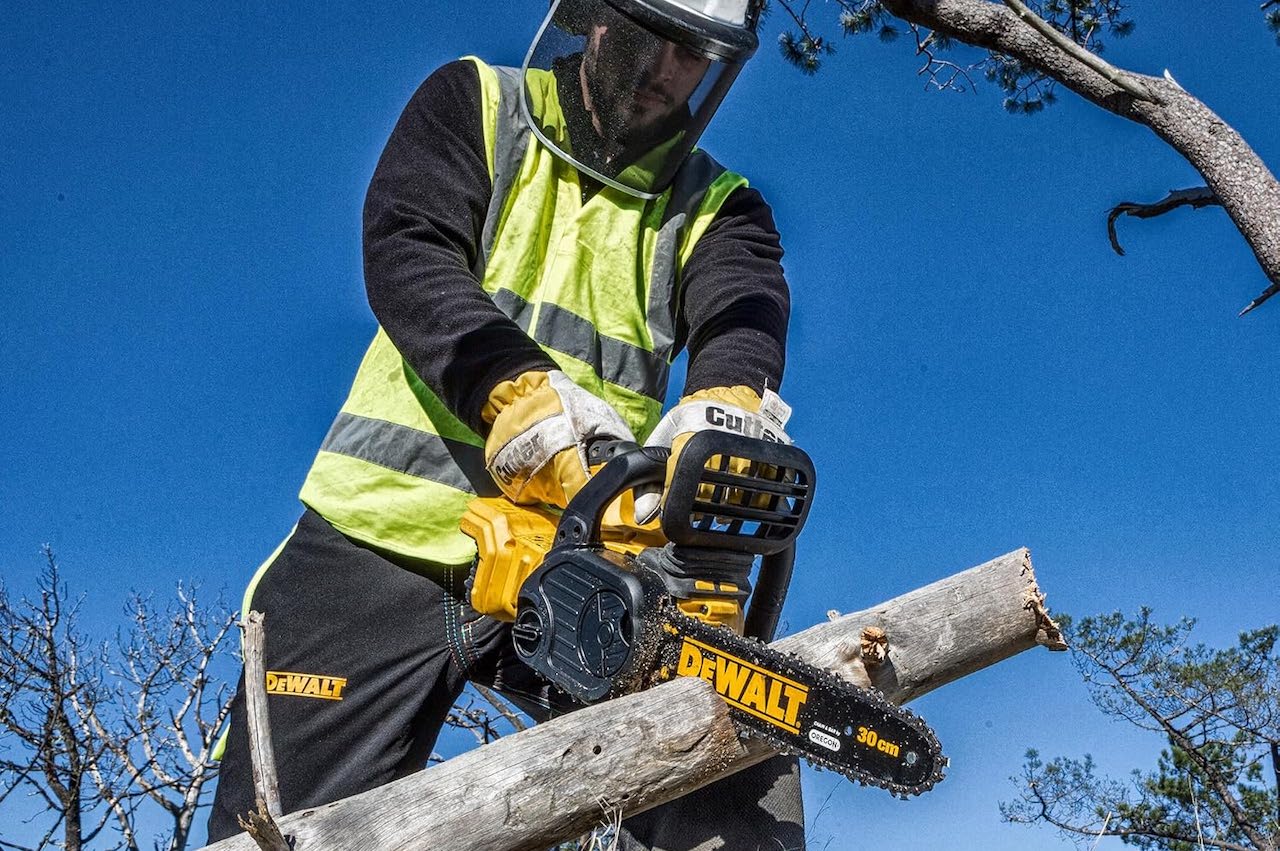 Un homme en train de couper une branche à l'aide d'une tronçonneuse DeWalt.
