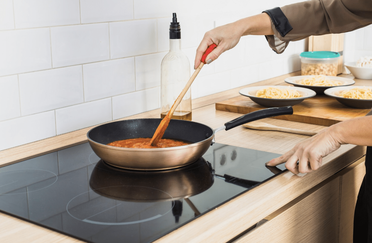 Une personne en train faire de la cuisine sur une plaque à induction.