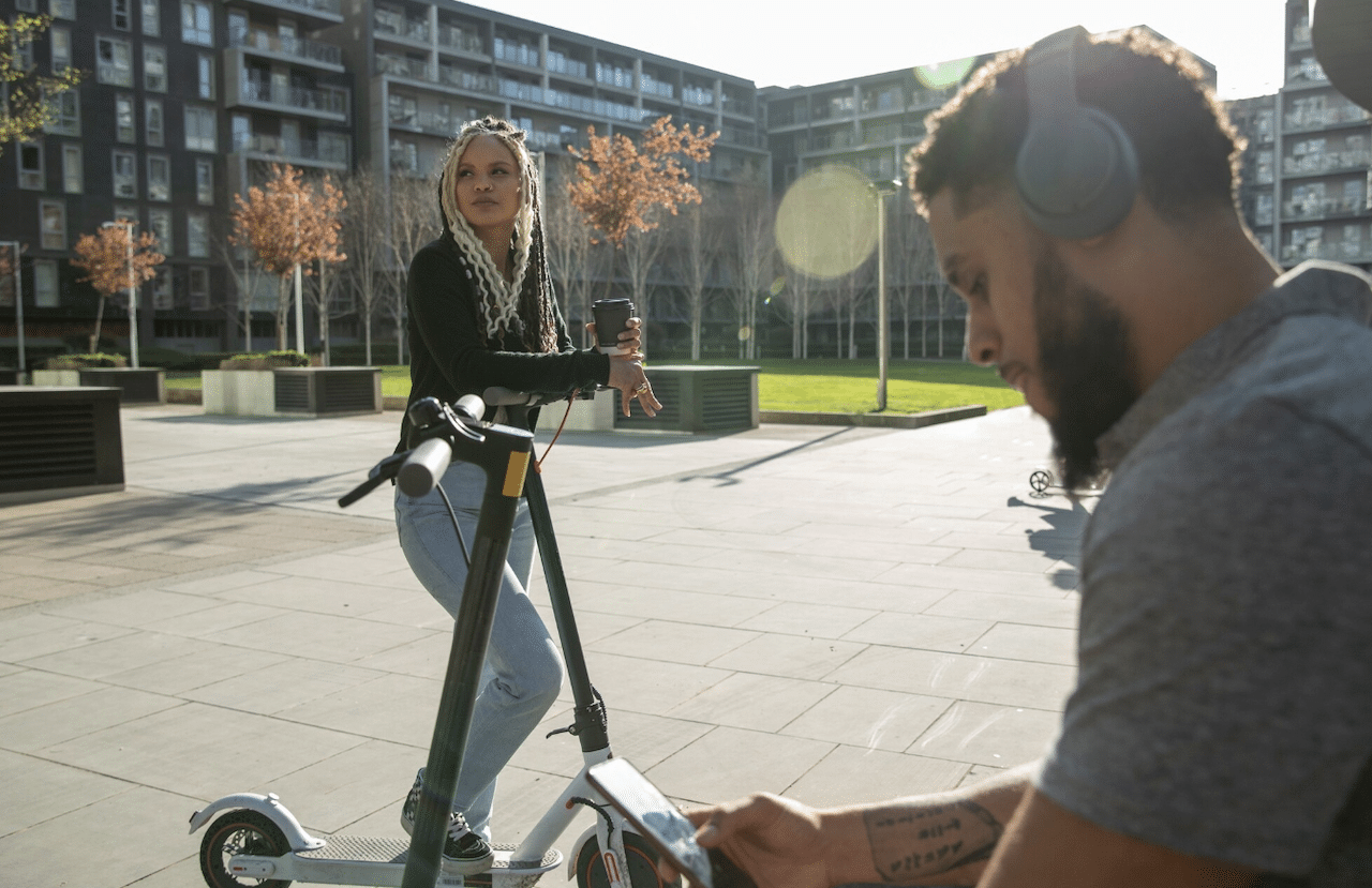 Deux personnes avec des trottinettes électriques.