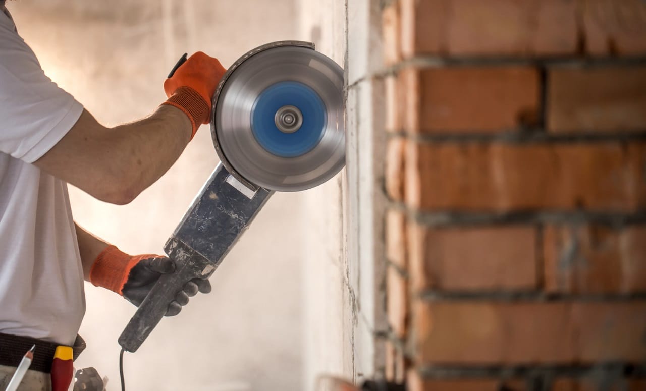 Un ouvrier tient une découpeuse à béton pour découper un mur