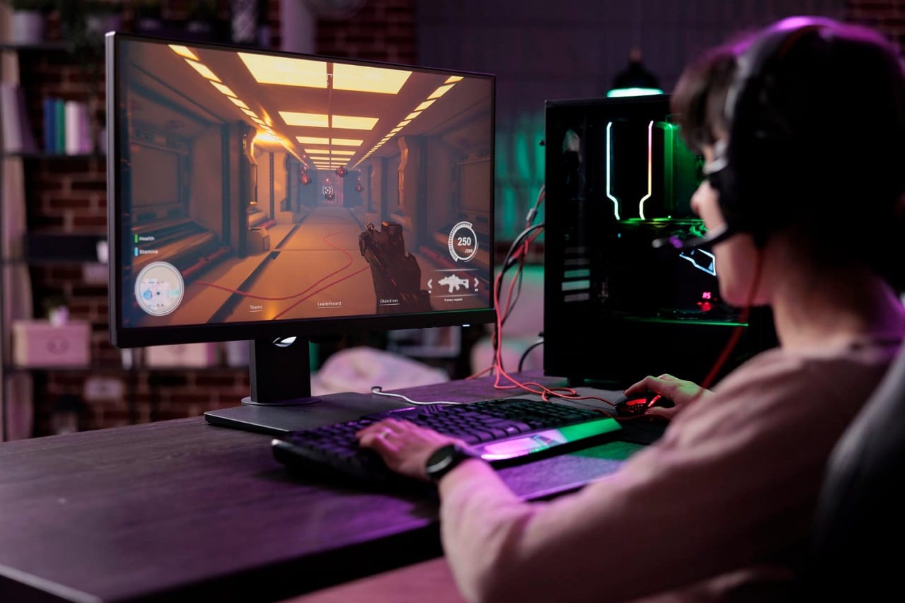 Un joueur vu de dos face à son écran PC Gamer sur lequel tourne un FPS