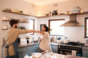 Shot of a happy young couple dancing in the kitchen while preparing breakfast at home