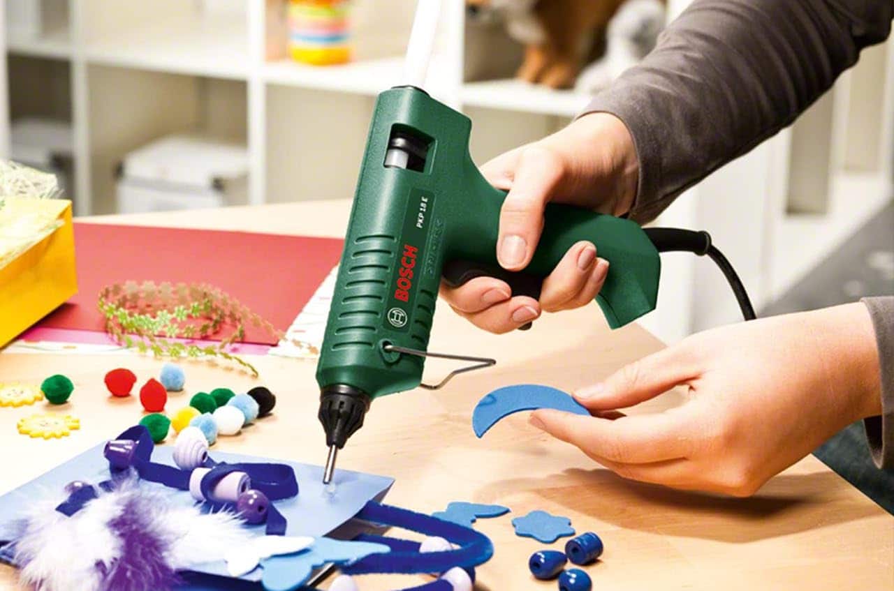 Un homme qui utilise un pistolet à colle de la marque Bosch.
