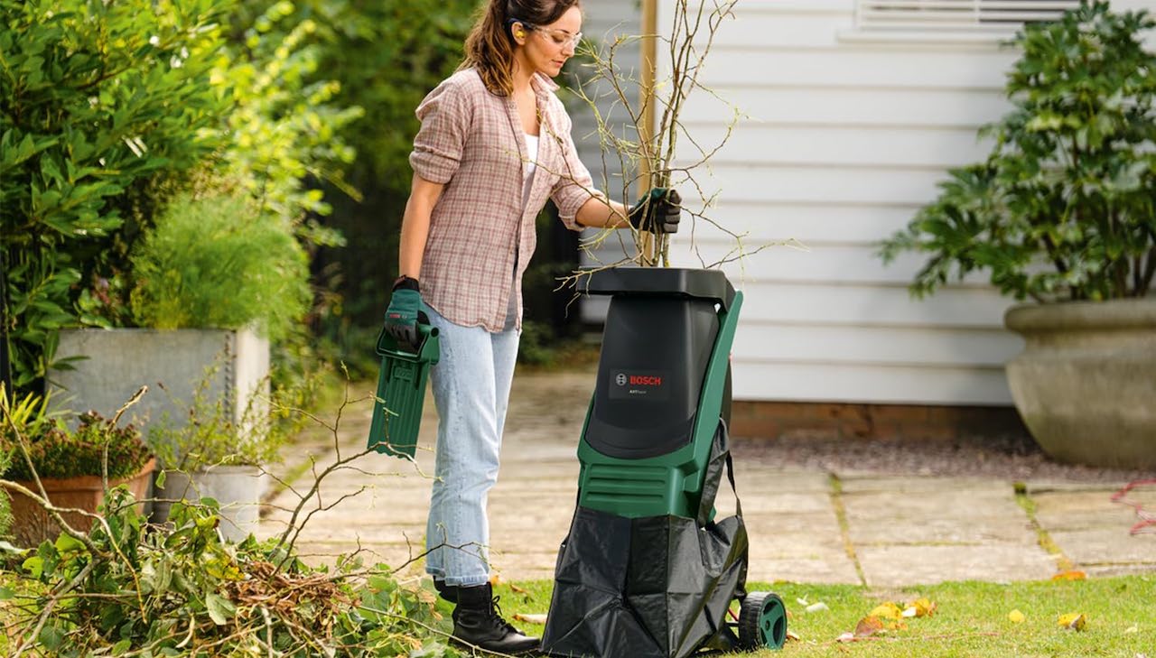 Une femme qui utilise un broyeur de végétaux de la marque Bosch.