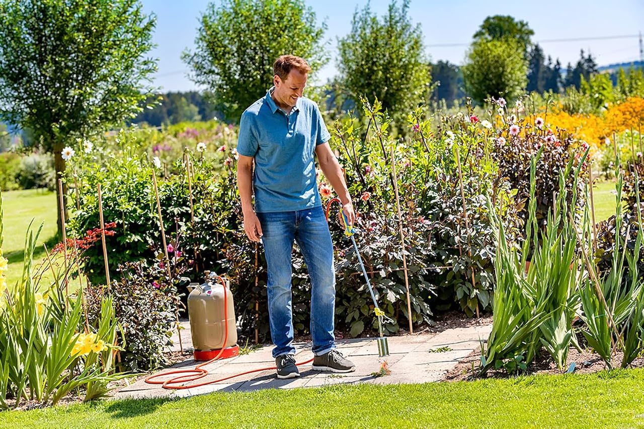 Un homme qui utilise un désherbeur thermique dans son jardin.