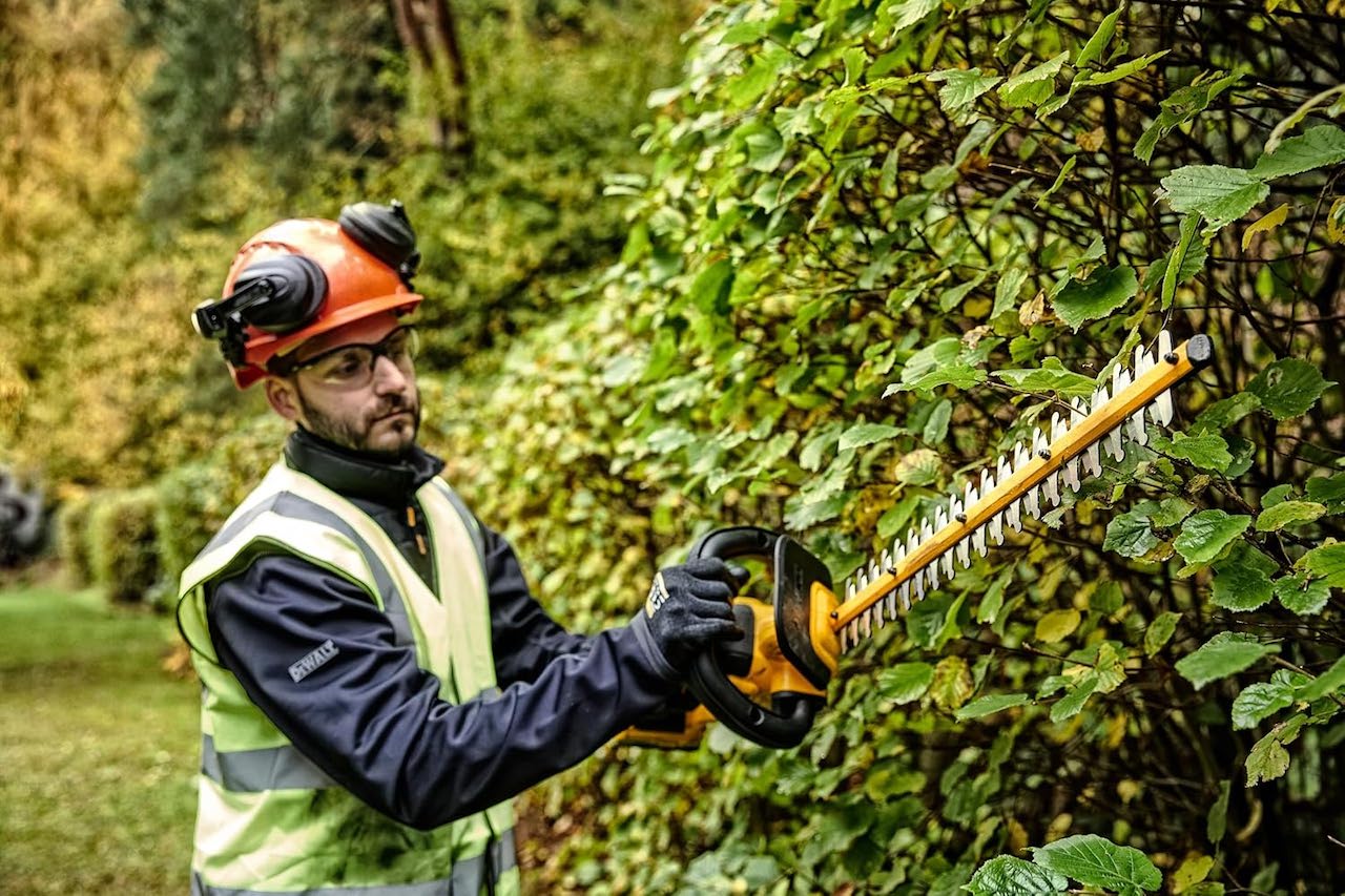 Un homme qui utilise un taille-haies électrique de la marque DeWalt.
