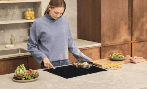 Une femme en train de cuisinier avec un plaque à induction.