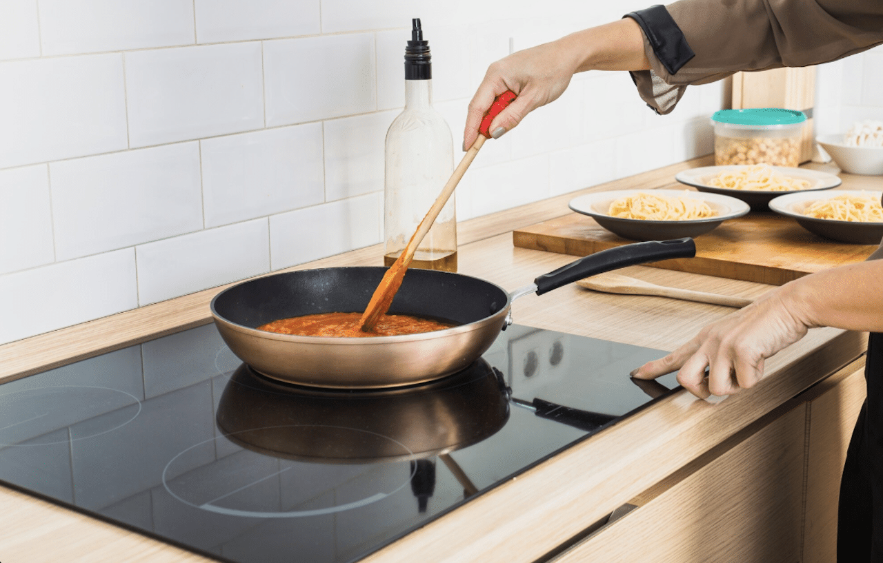 Une personne en train de cuisiner sur une plaque de cuisson vitrocéramique.