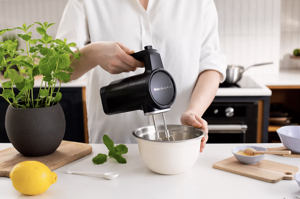 Une femme qui utilise un batteur électrique de la marque Kenwood.