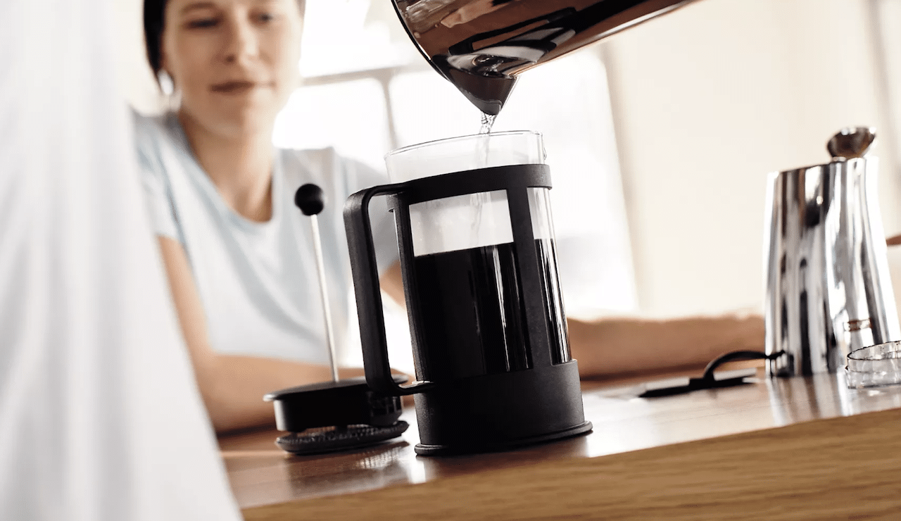 Une femme qui se sert du café depuis une cafetière italienne.