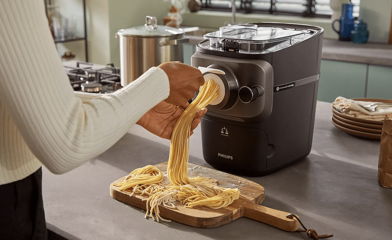 Une femme qui prépare des spaghettis à l'aide d'une machine à pâtes. 