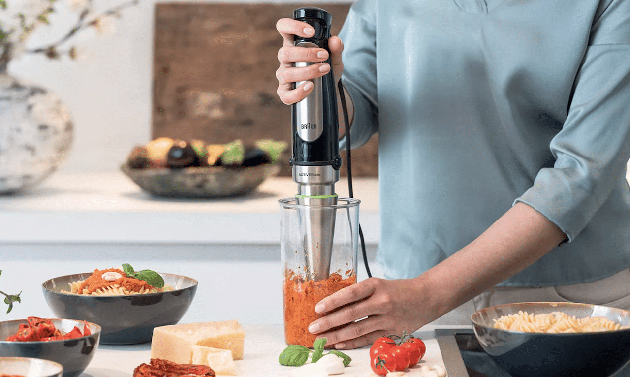 Une femme qui utilise un mixeur plongeant.