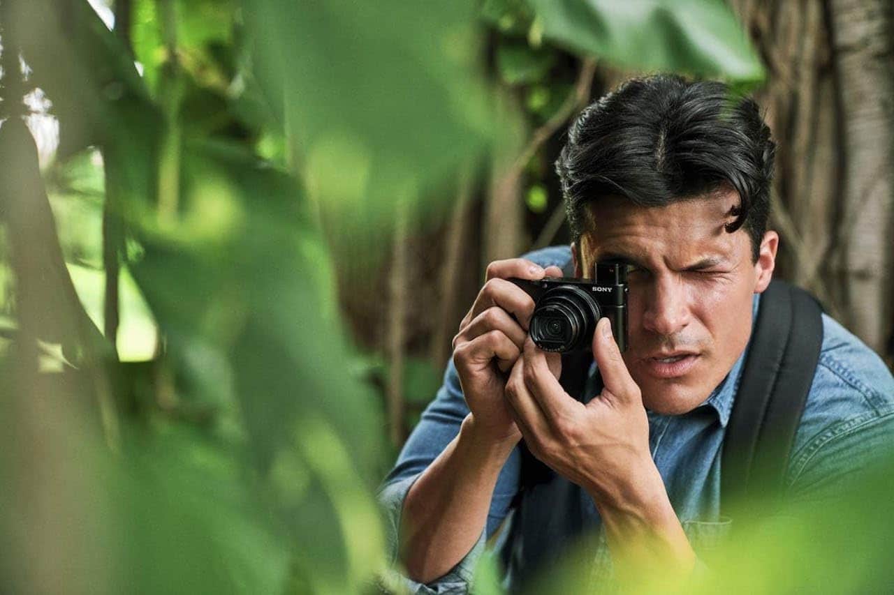 Un homme qui utilise un appareil photo compact en forêt.