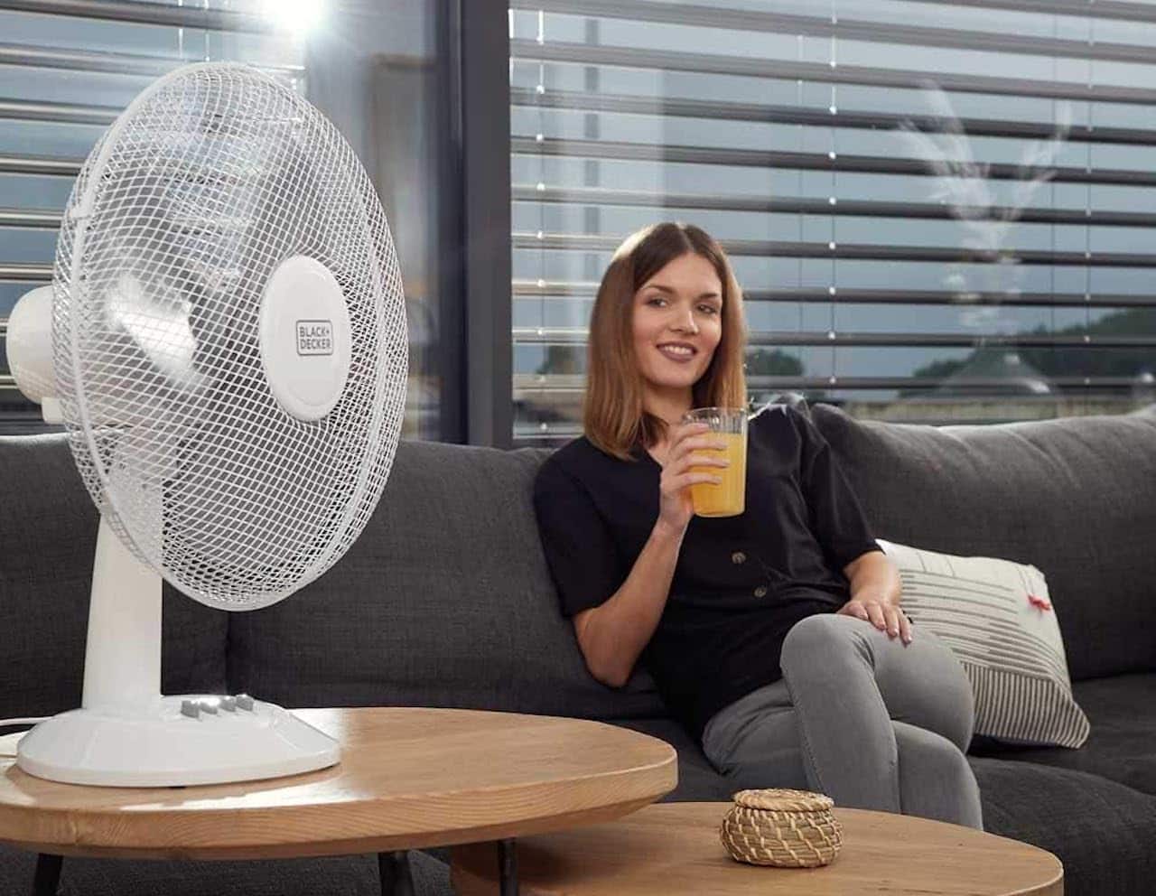 Une femme qui se rafraîchit à l'aide d'un ventilateur de table.