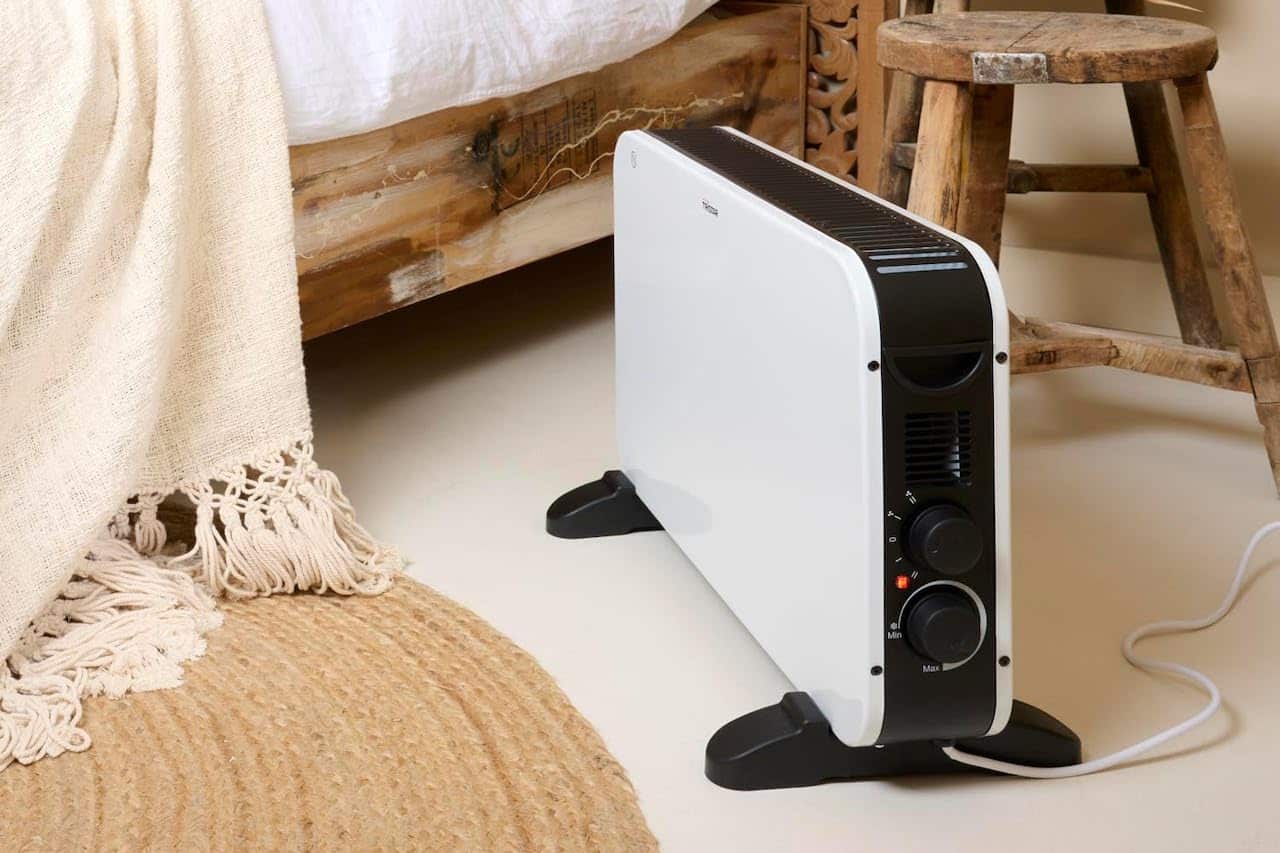 Un convecteur électrique à côté d'un lit.
