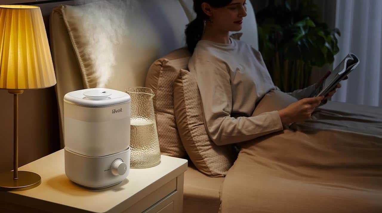 Une femme dans sa chambre avec un humidificateur d'air sur la table de chevet.