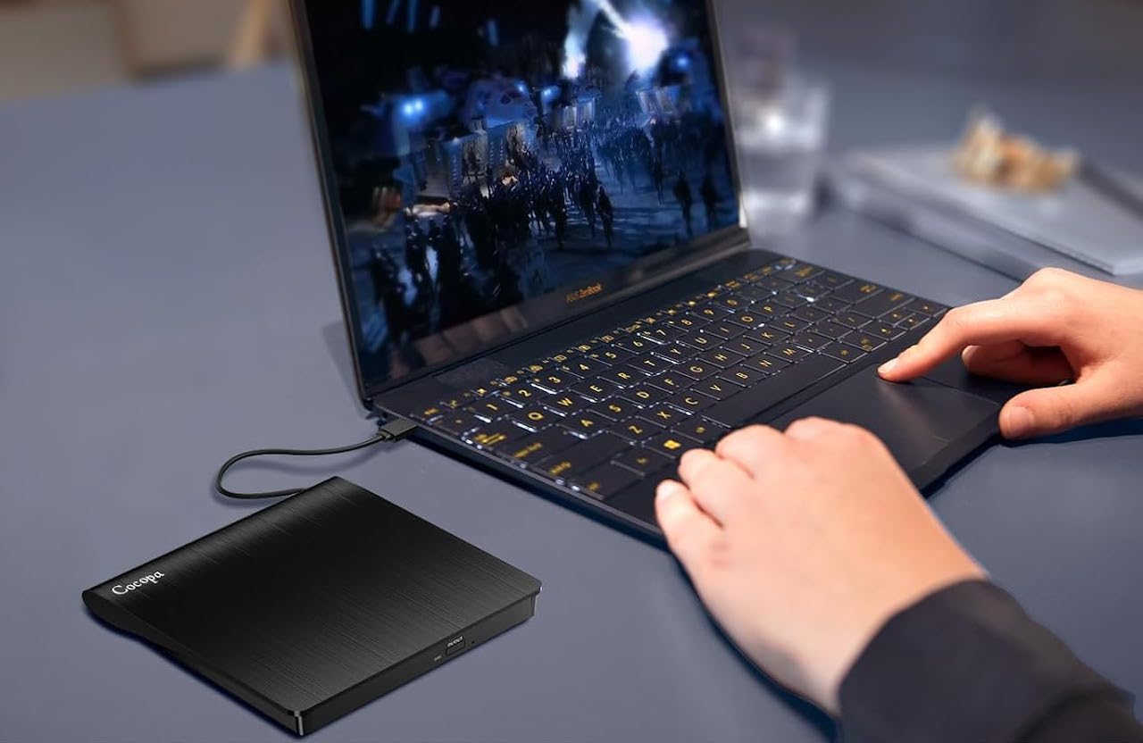 Une personne qui utilise un ordinateur et un lecteur CD.