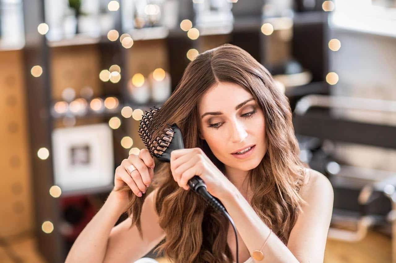 Une femme qui utilise une brosse lissante sur ses cheveux.