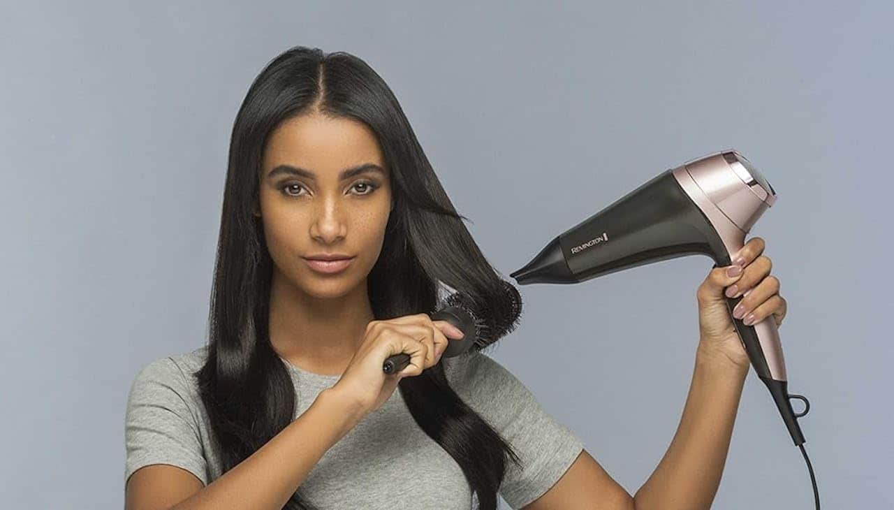 Une femme qui utilise un sèche-cheveux ionique.