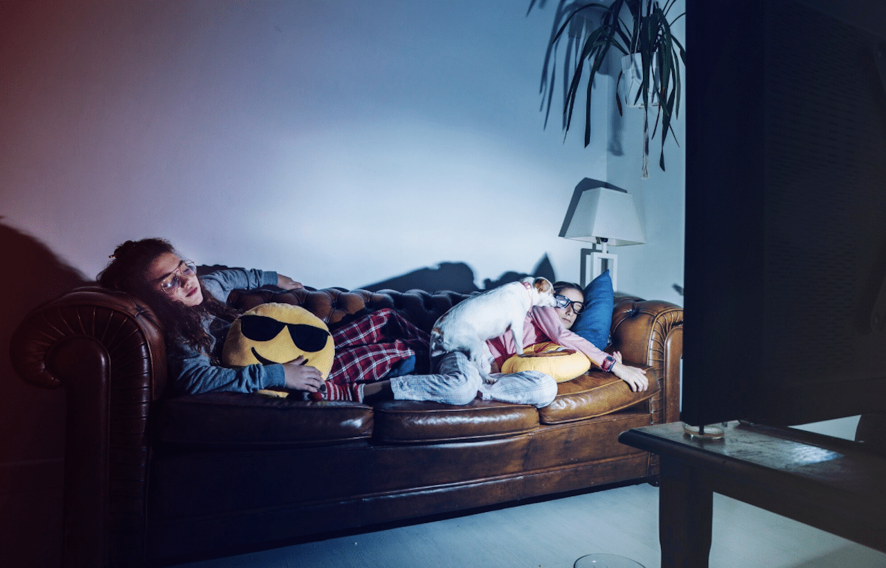 Deux filles sur un canapé qui regarde la télévision dans un home cinéma.