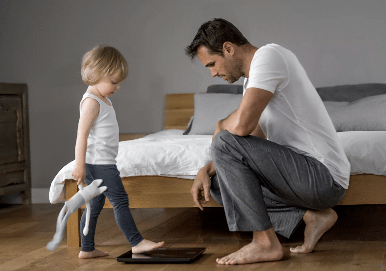 Un père et son enfant qui utilise un pèse-personne de la marque Withings.