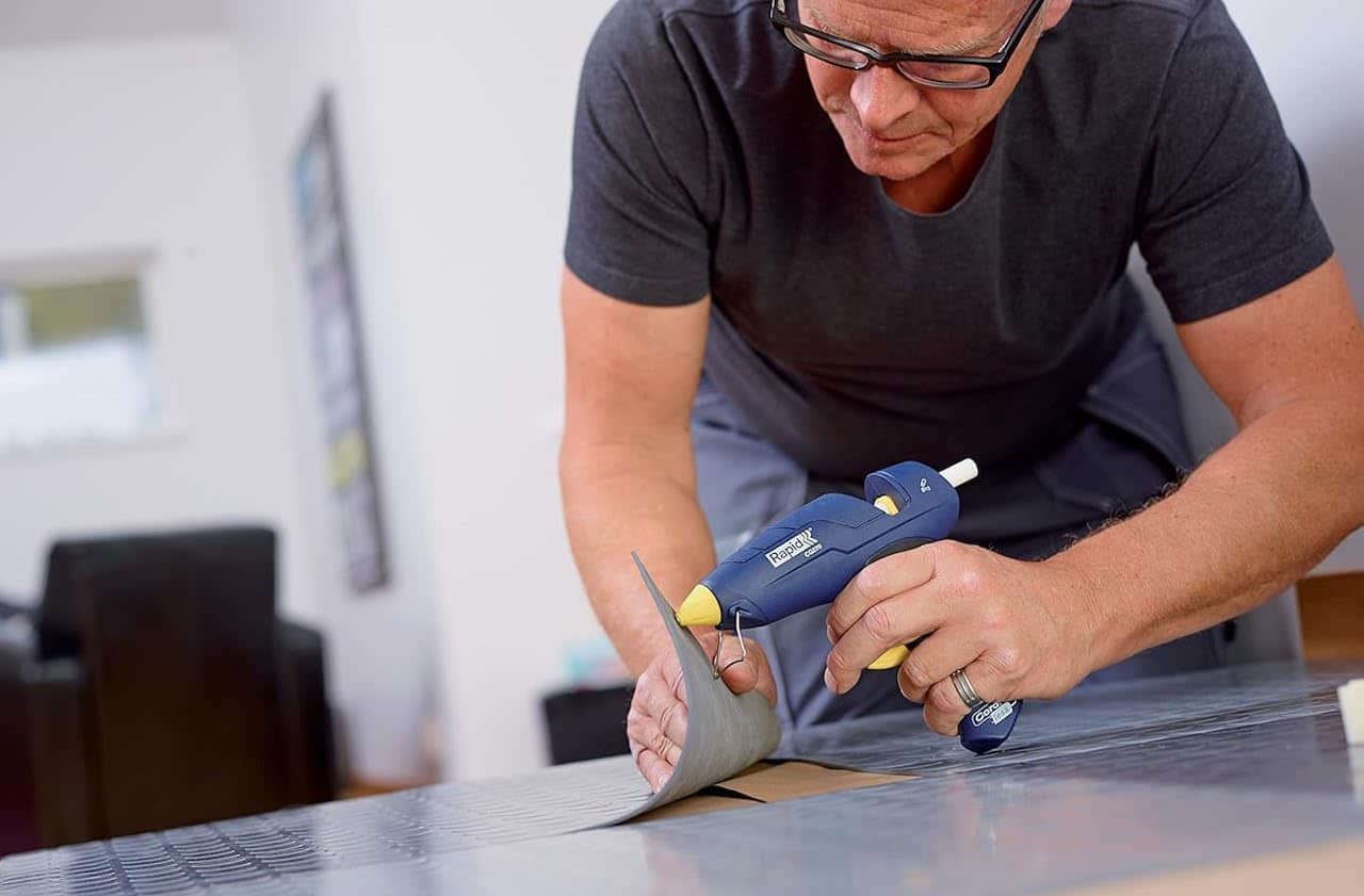 Un homme qui utilise un pistolet à colle.
