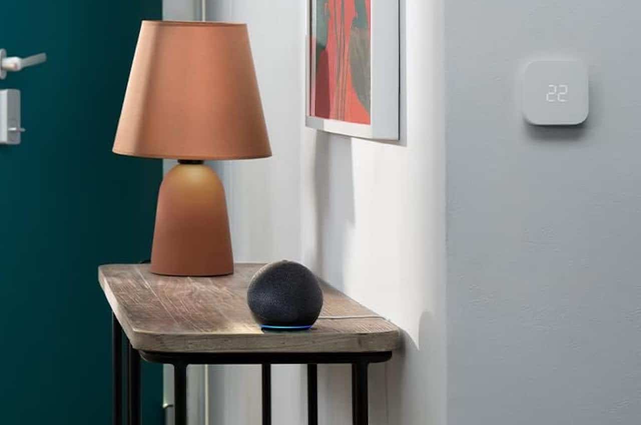 Un assistant vocal posé sur un buffet à l'entrée d'une maison moderne.