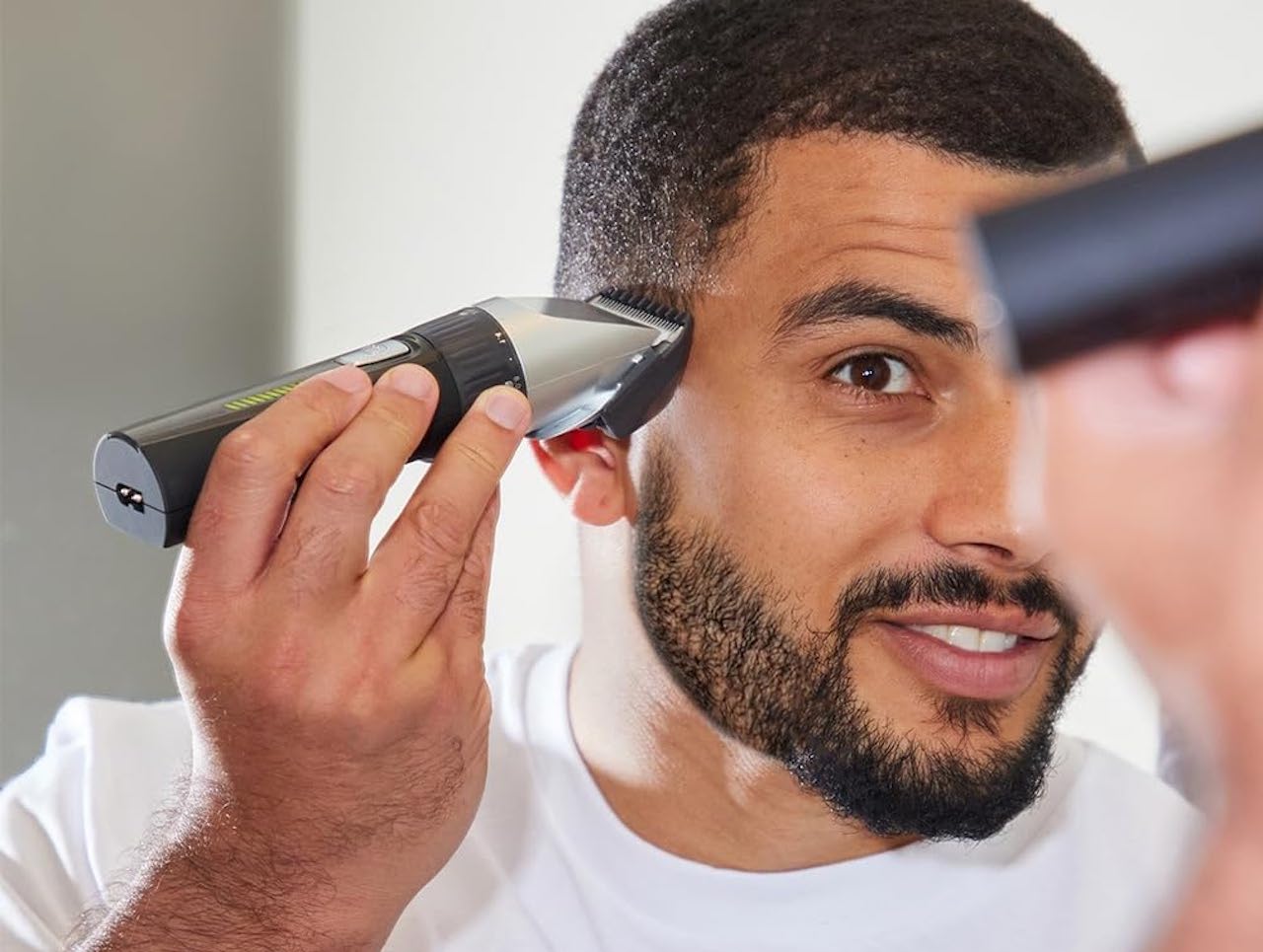 Un homme qui utilise une tondeuse à cheveux dans sa salle de bain.