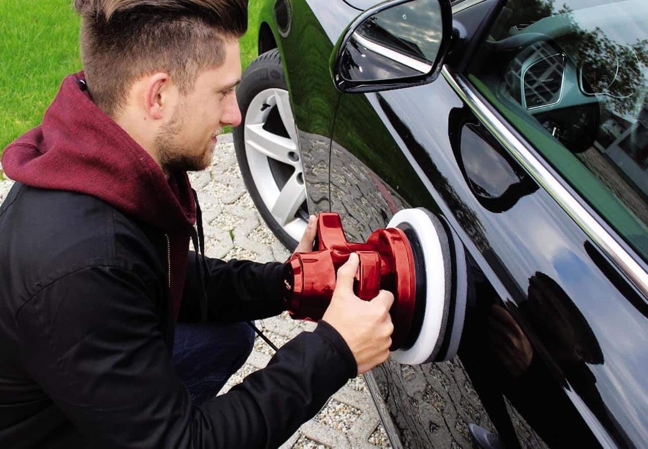 Un homme qui utilise une polisseuse sur sa voiture.