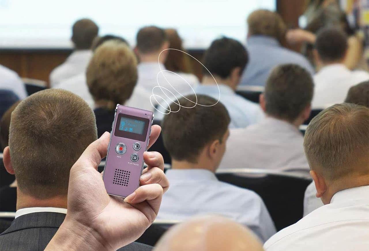 Une personne qui utilise un dictaphone lors d'un conférence.